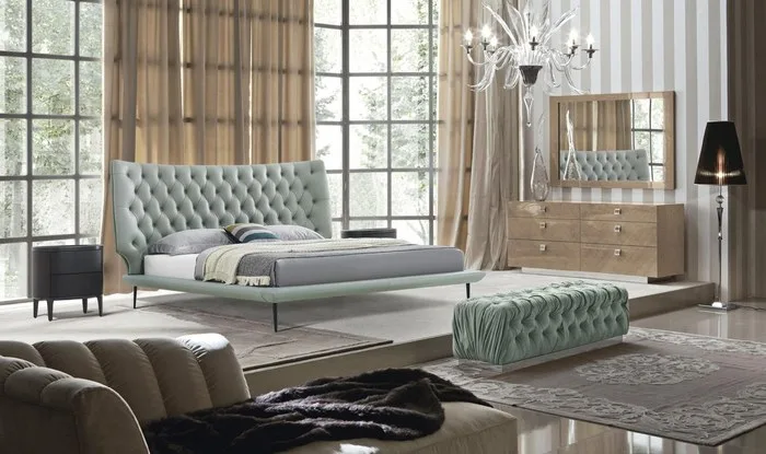 Bedroom with a mint tufted bed, a matching bench and a crystal chandelier