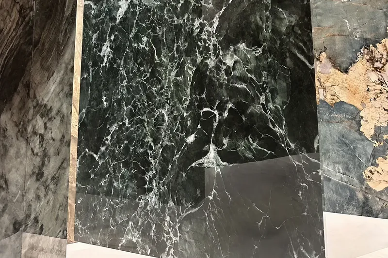 Dark green marble-look slab with dense white veining on a showroom frame