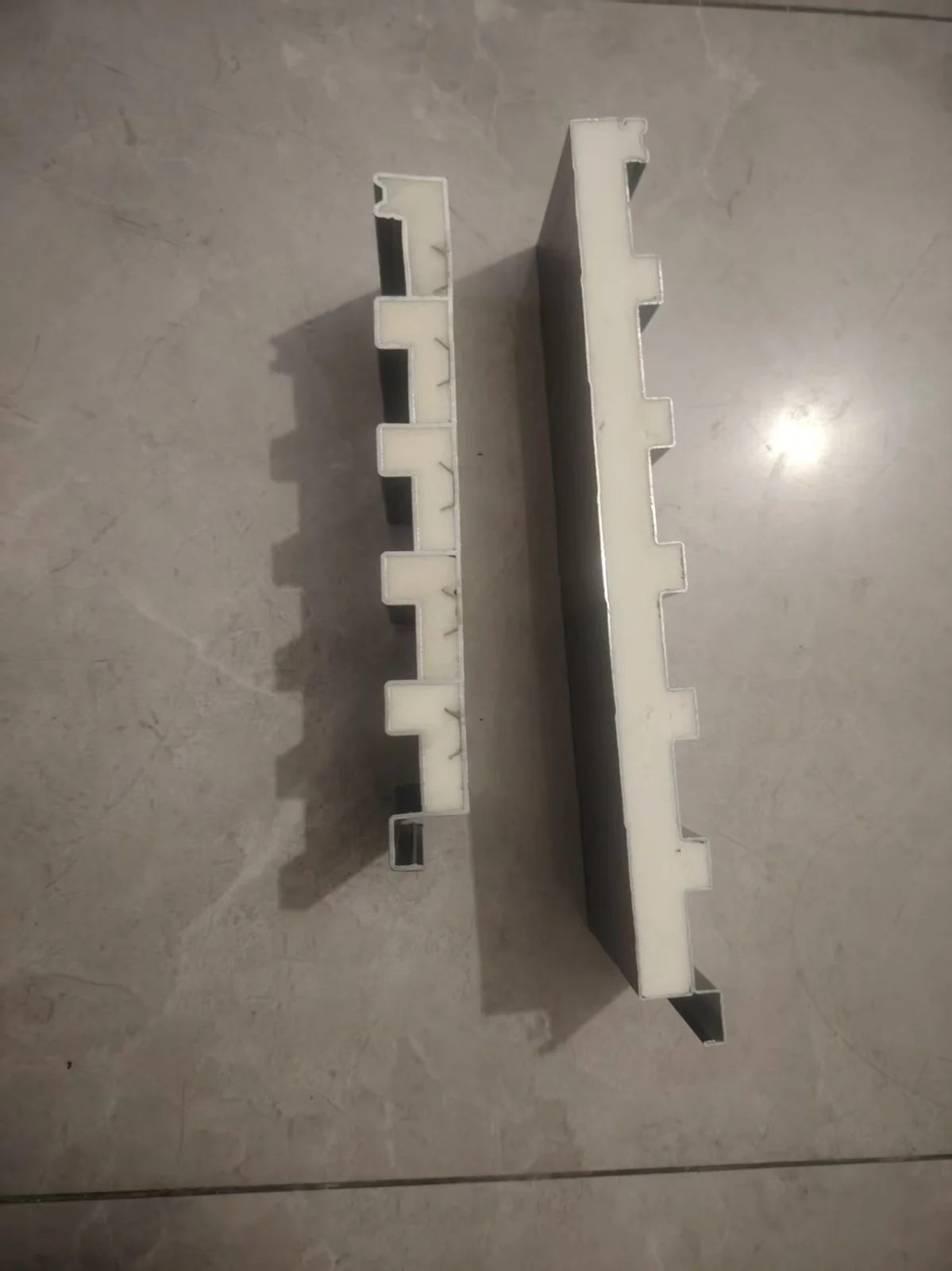 Two insulated roof panel samples edge-on with their foam cores exposed