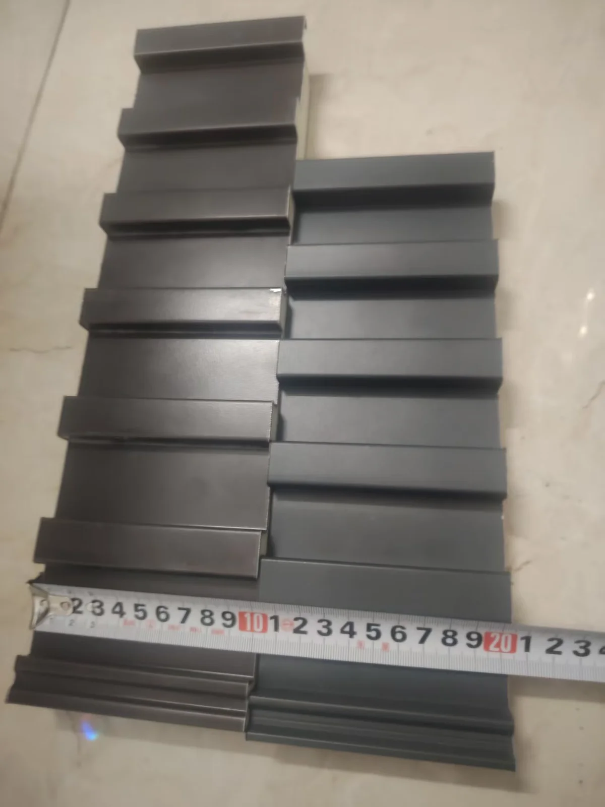 The same two stacks of roof panel samples seen from the side, with a tape measure laid across them