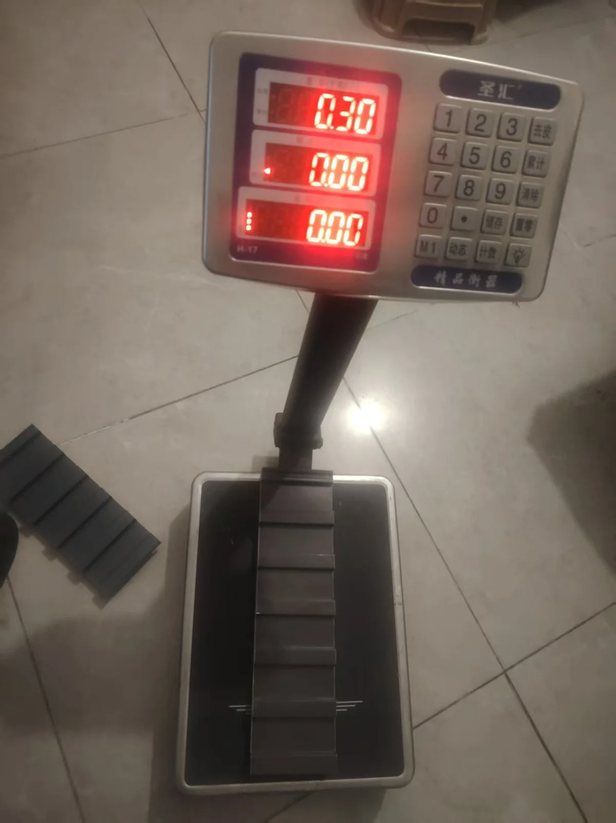 A digital bench scale reading 0.30, with a long insulated roof panel sample lying on the platform