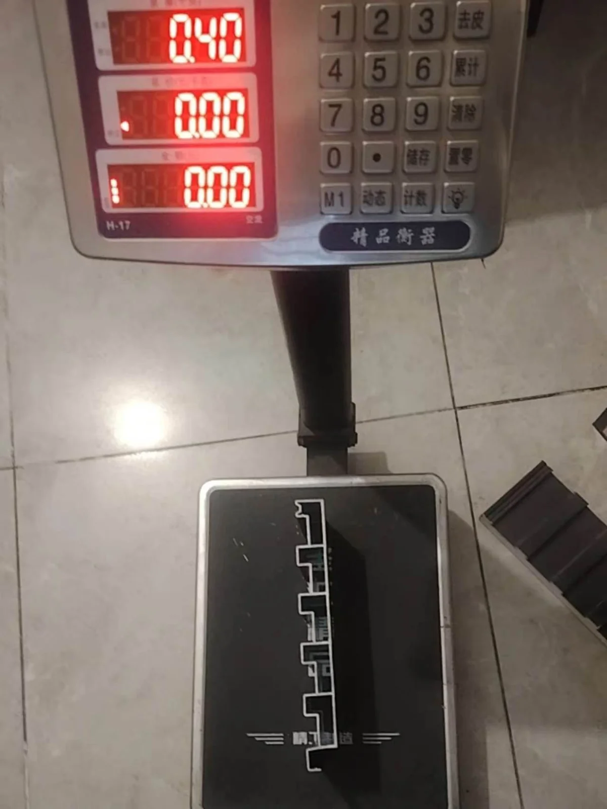 A digital bench scale reading 0.40, with a small roof panel sample on the platform, its core removed