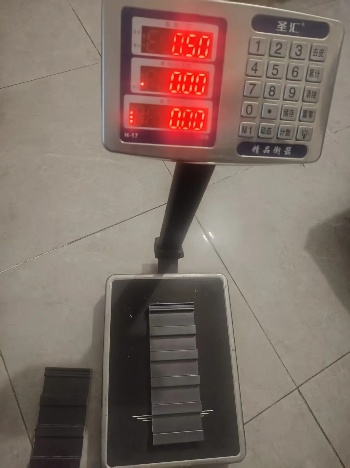 A digital bench scale reading 0.50, with a small insulated roof panel sample on the platform